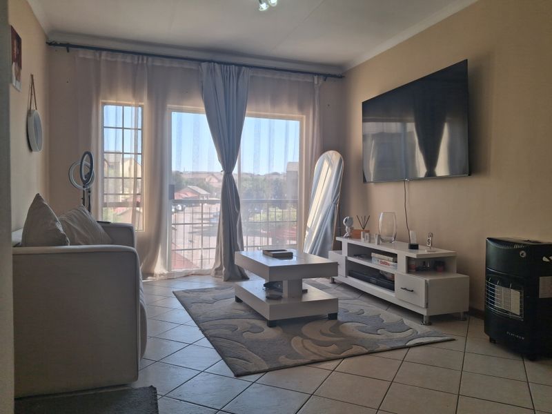 A comfortable living room featuring tiled flooring and a large sliding glass door that provides natural light and access to the exterior.