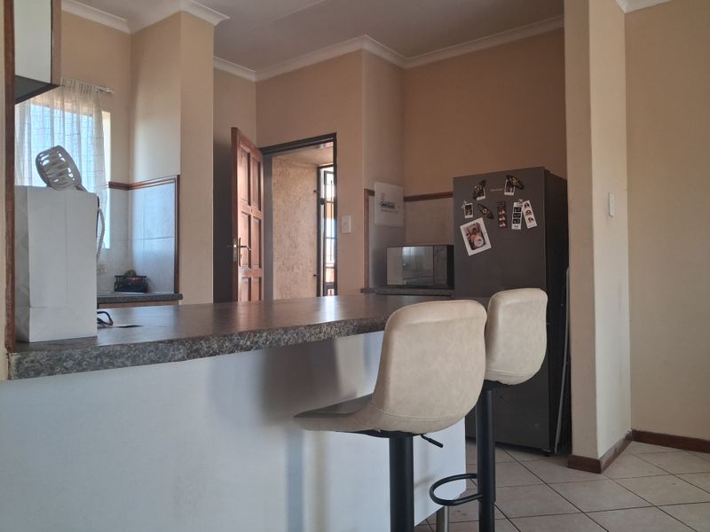 A functional kitchen area featuring a breakfast bar, tiled flooring, and neutral wall tones, providing a practical space for daily meal preparation.