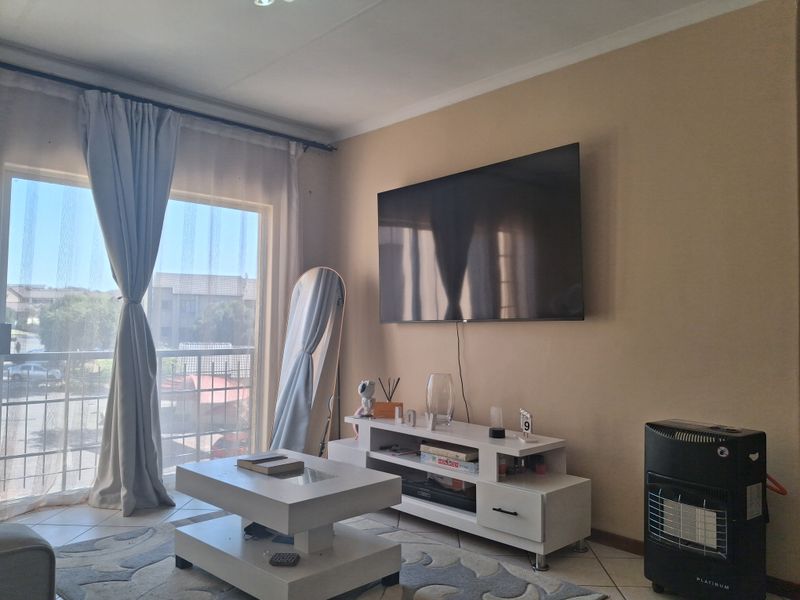 A living room featuring tiled flooring and a large sliding glass door providing access to a balcony.