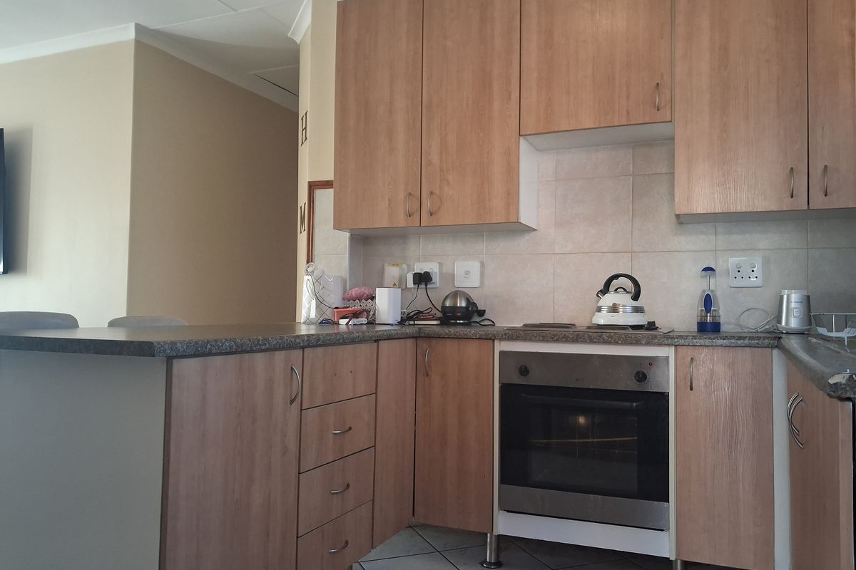 A functional kitchen featuring light wood-look cabinetry, laminate countertops, a built-in oven, and a tiled backsplash, offering a practical layout for daily use.