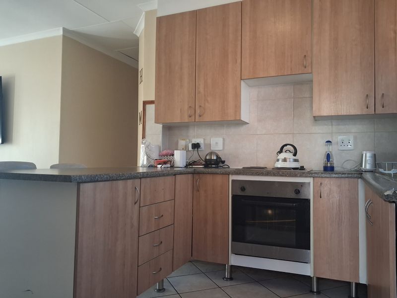 A functional kitchen featuring light wood-look cabinetry, laminate countertops, a built-in oven, and a tiled backsplash, offering a practical layout for daily use.