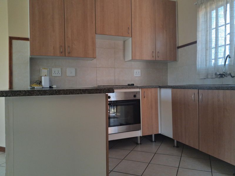 A functional kitchen featuring light wood-finish cabinetry, laminate countertops, a built-in oven, and tiled flooring, offering a clean and practical workspace.