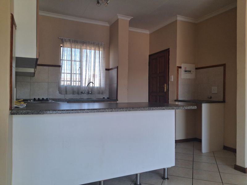 A functional kitchen featuring built-in cabinetry, laminate countertops, a hob, and tiled flooring, offering a clean and practical layout for daily use.