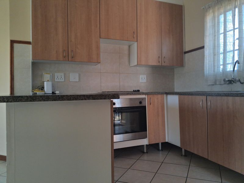 A functional kitchen featuring laminate cabinetry, built-in oven, hob, and tiled backsplash, offering a practical layout ready for modern updates.
