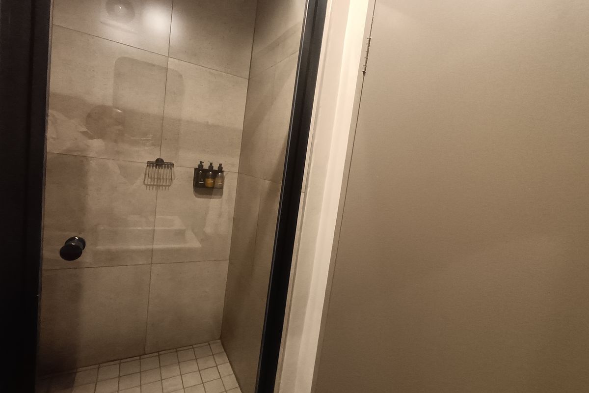 A modern walk-in shower featuring neutral wall tiles, a glass enclosure, and a tiled floor, presenting a clean and functional bathroom space.