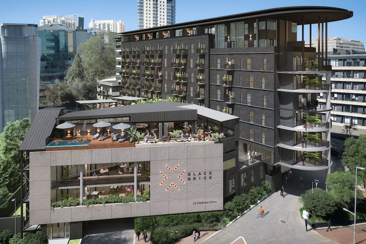Aerial view of the Black Brick apartment complex featuring a modern multi-story facade, rooftop pool, and outdoor entertainment deck.