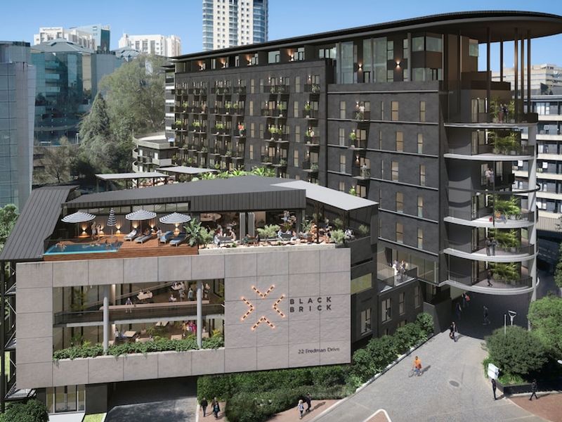 Aerial view of the Black Brick apartment complex featuring a modern multi-story facade, rooftop pool, and outdoor entertainment deck.