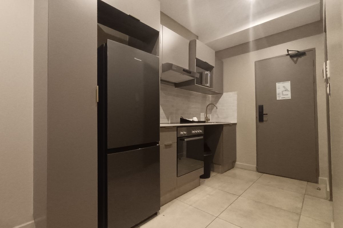 Compact modern kitchen featuring built-in cabinetry, integrated oven, extractor fan, and tiled flooring, providing a functional and efficient culinary space.