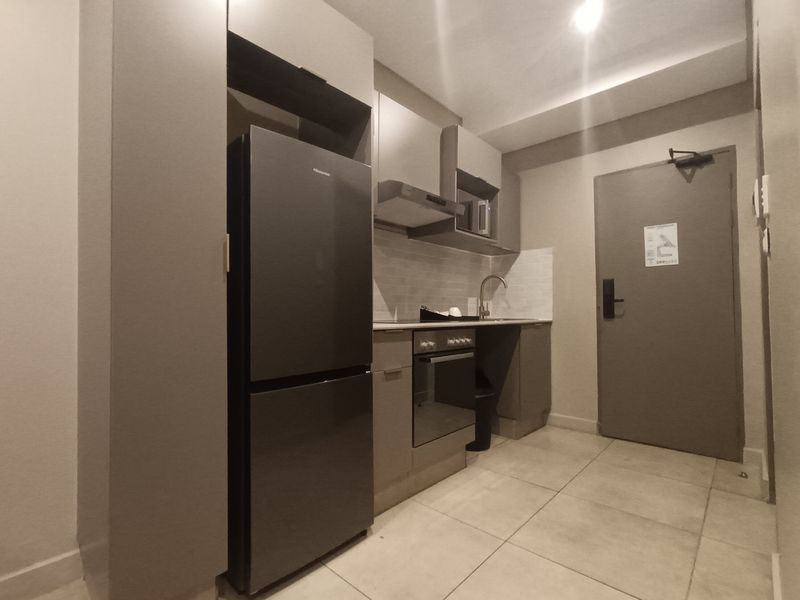 Compact modern kitchen featuring built-in cabinetry, integrated oven, extractor fan, and tiled flooring, providing a functional and efficient culinary space.