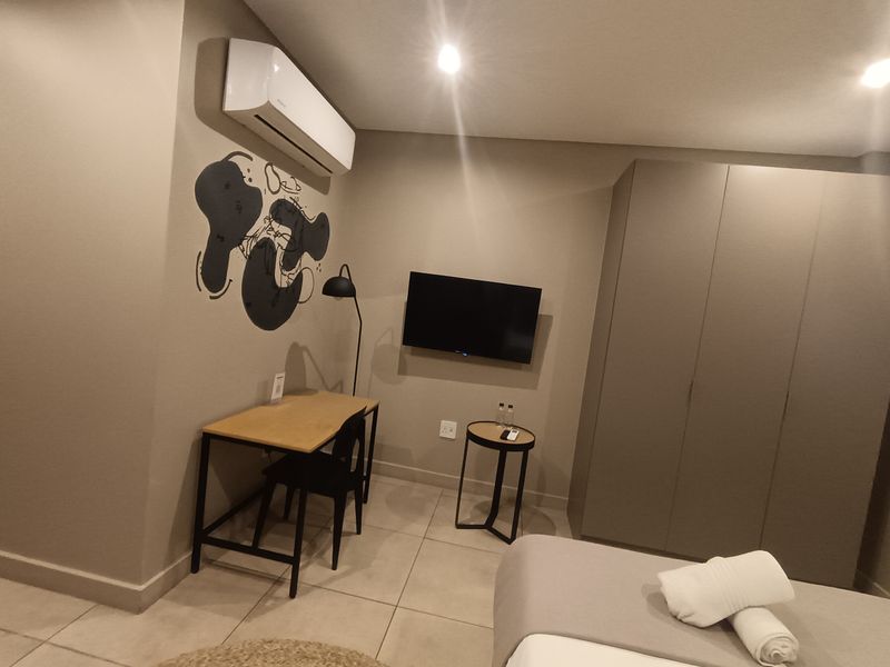 A modern bedroom featuring tiled flooring, a built-in wardrobe, and a wall-mounted air conditioning unit.