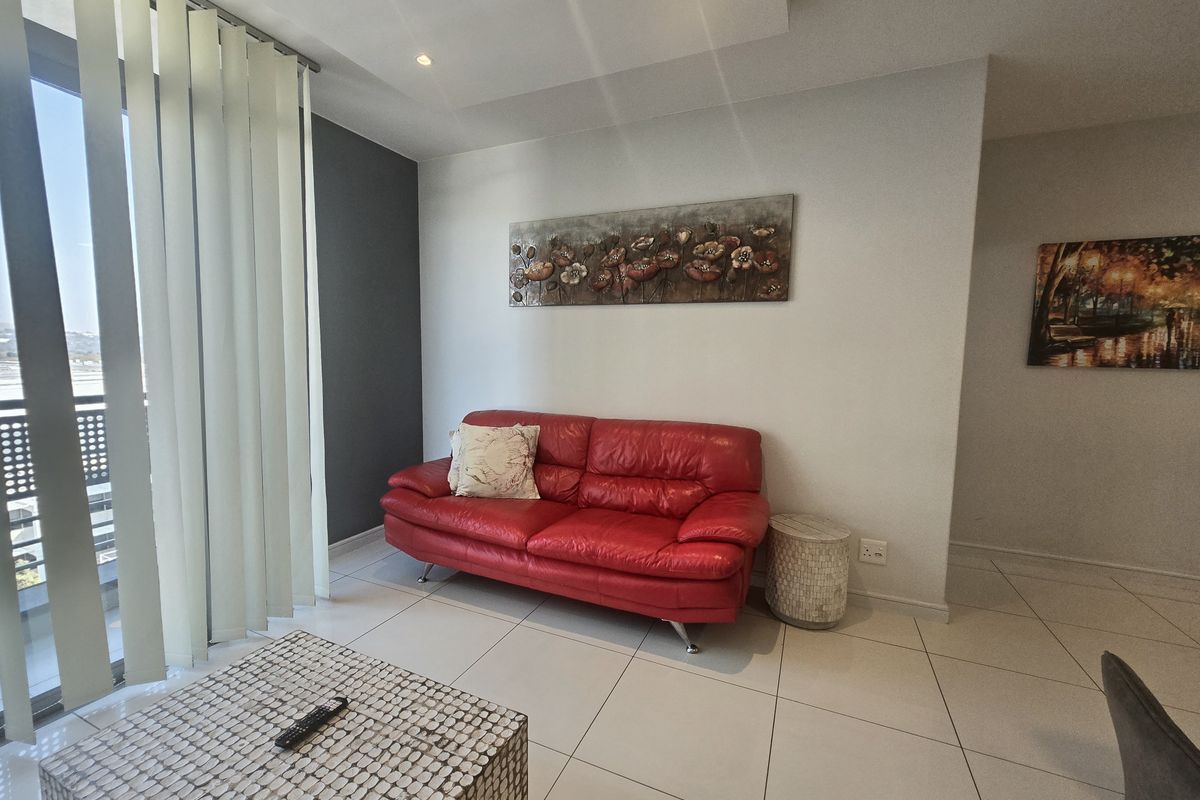 A bright living room featuring tiled flooring, recessed ceiling lights, and a large sliding glass door with vertical blinds leading to an outdoor area.