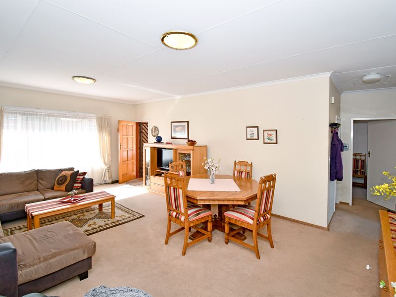 Open plan living and dining area featuring neutral wall tones, carpeted flooring, and flush mount ceiling lighting.