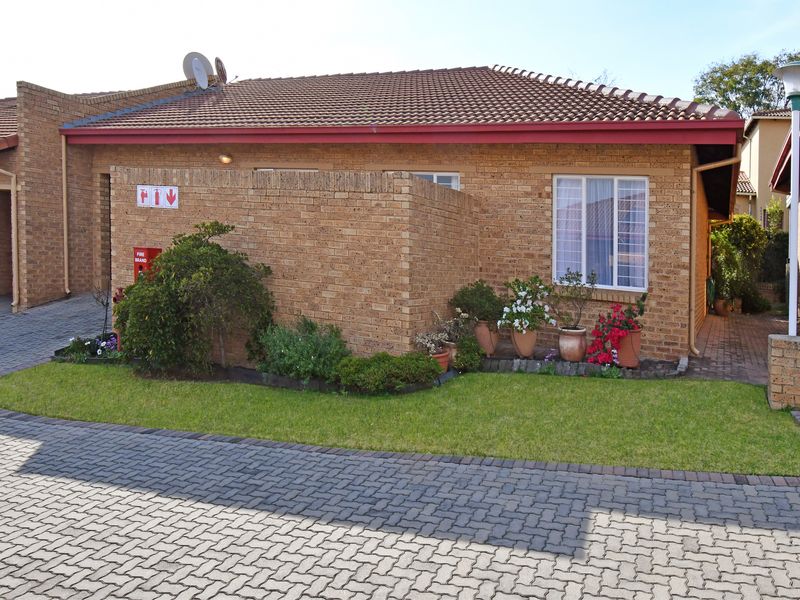 Front view of a face brick residential unit featuring a tiled roof, paved driveway, and established garden area.