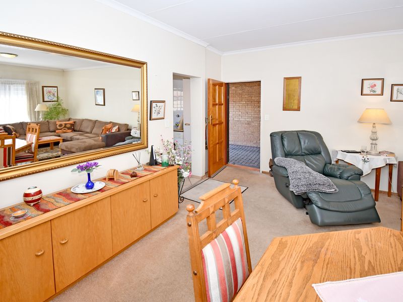 A comfortable living area featuring neutral walls, coved ceilings, and built-in cabinetry, providing a functional space with direct access to the exterior.