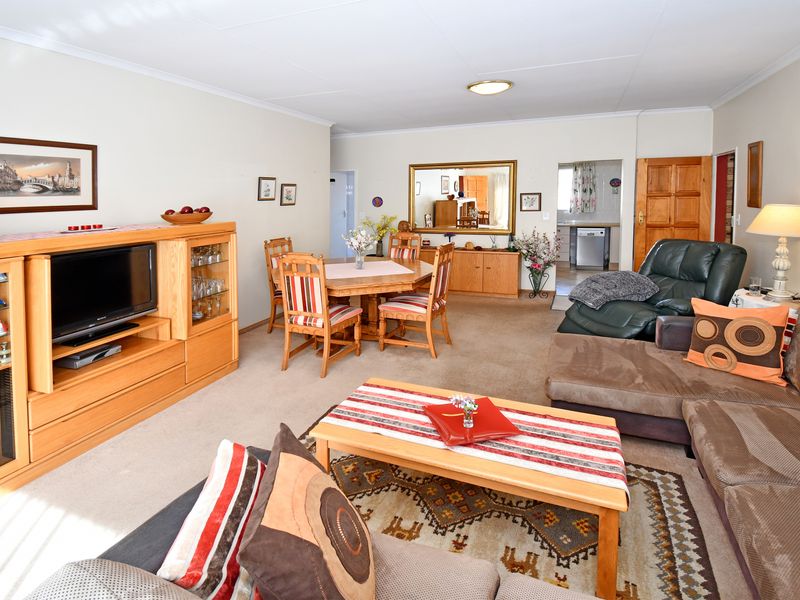 Spacious open-plan living and dining area featuring neutral walls, carpeted flooring, and direct access to the kitchen area.