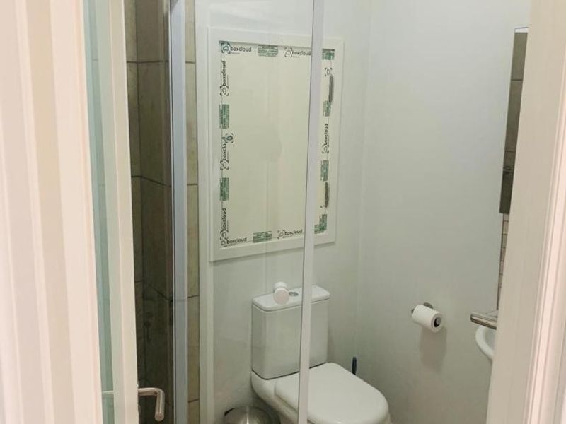 A compact bathroom featuring a shower enclosure, toilet, and tiled finishes. The space is clean and functional, ready for final finishing touches.
