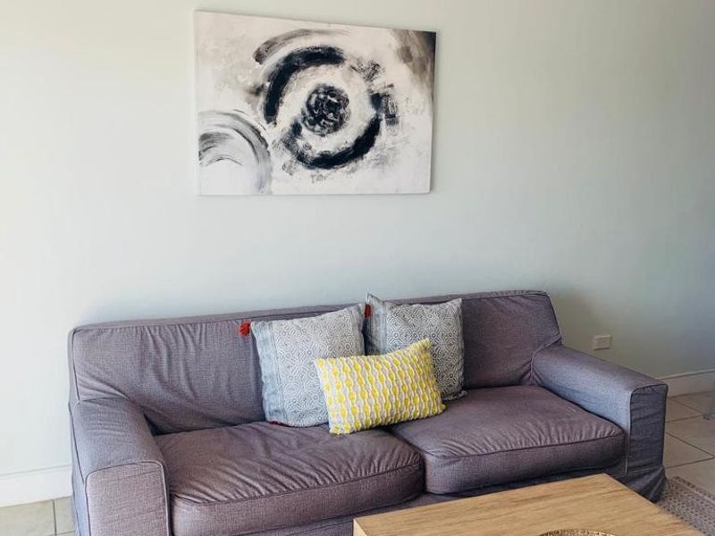 A living room area featuring neutral wall tones and tiled flooring, providing a functional and comfortable space for relaxation.