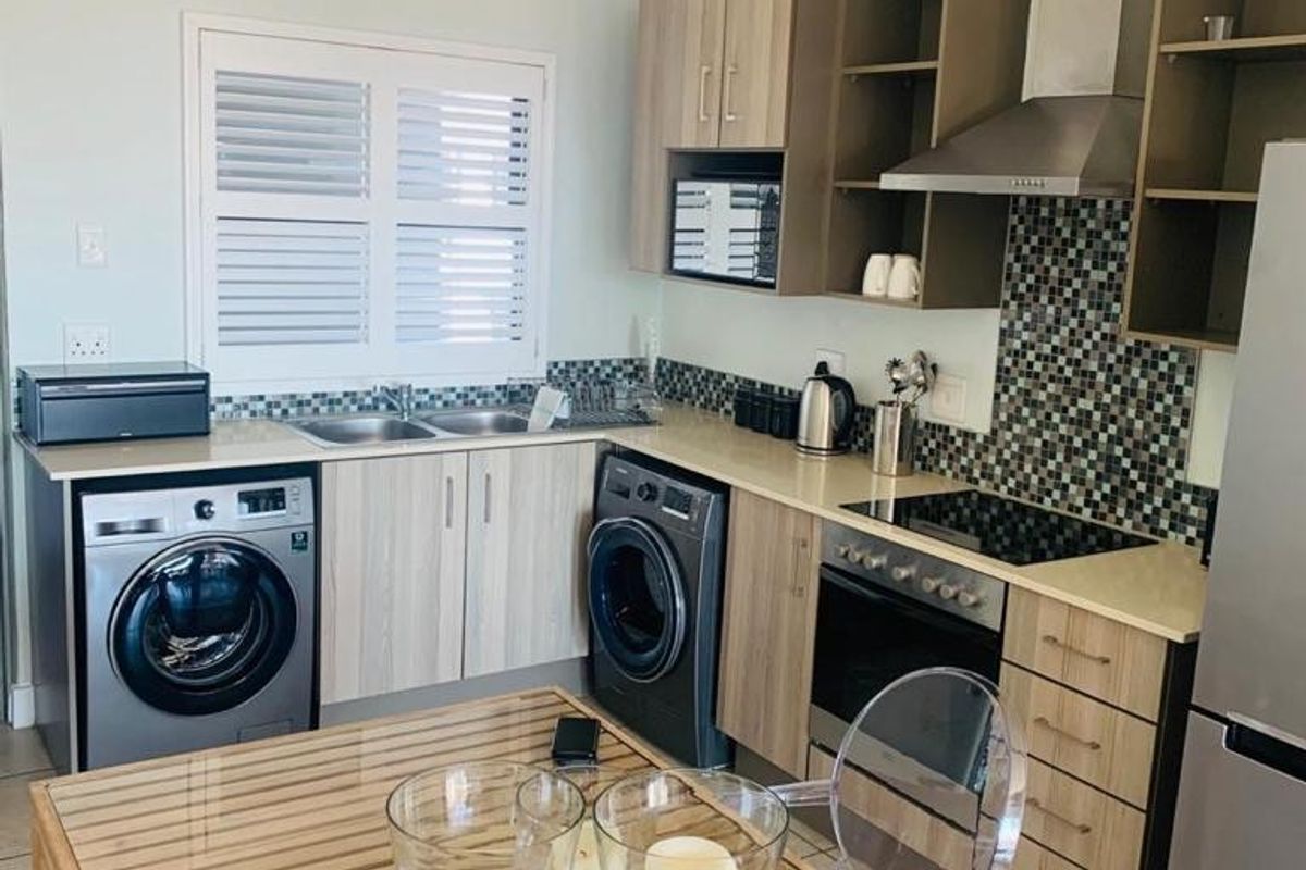 A functional kitchen featuring wood-finish cabinetry, mosaic tile backsplash, integrated appliances, and a built-in oven with an extractor fan.