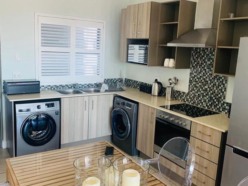 A functional kitchen featuring wood-finish cabinetry, mosaic tile backsplash, integrated appliances, and a built-in oven with an extractor fan.