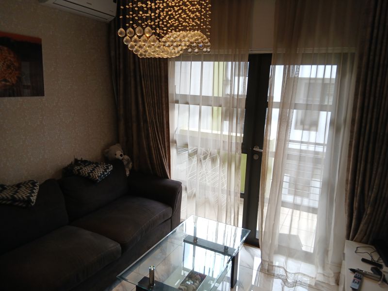 A cozy living room featuring tiled flooring, textured wallpaper, and a glass sliding door providing access to an outdoor area.