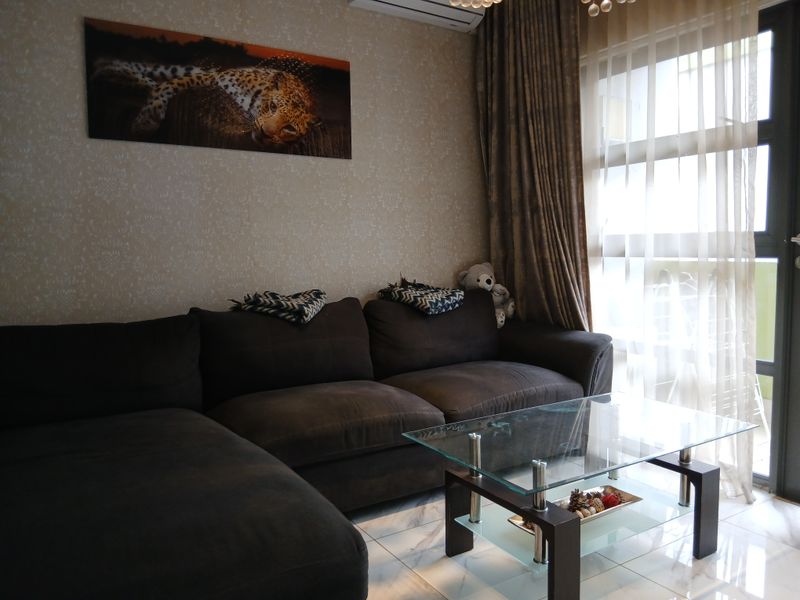 A comfortable living room featuring tiled flooring, an air conditioning unit, and a large sliding glass door providing natural light.