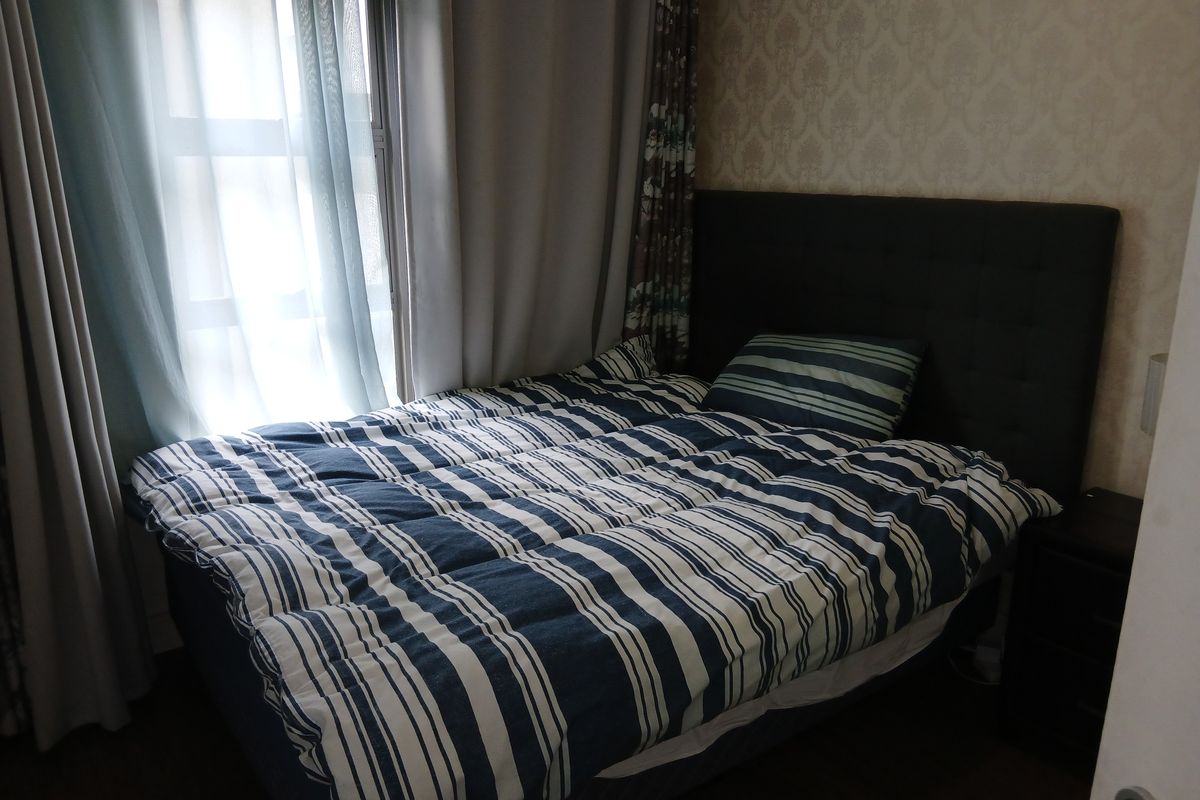 A cozy bedroom featuring patterned wallpaper and laminate flooring, providing a comfortable and functional sleeping space.