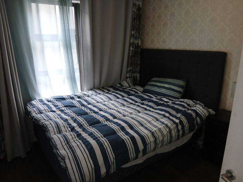 A cozy bedroom featuring patterned wallpaper and laminate flooring, providing a comfortable and functional sleeping space.