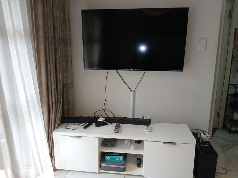 A living room area featuring tiled flooring and a wall-mounted television setup with integrated cable management.