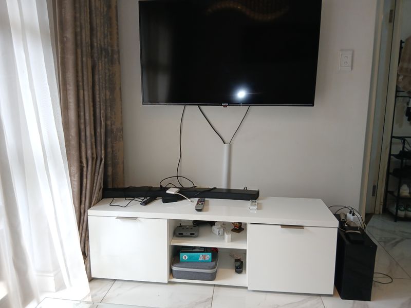 Living room area featuring marble-look floor tiles and a wall-mounted television setup with cable management.