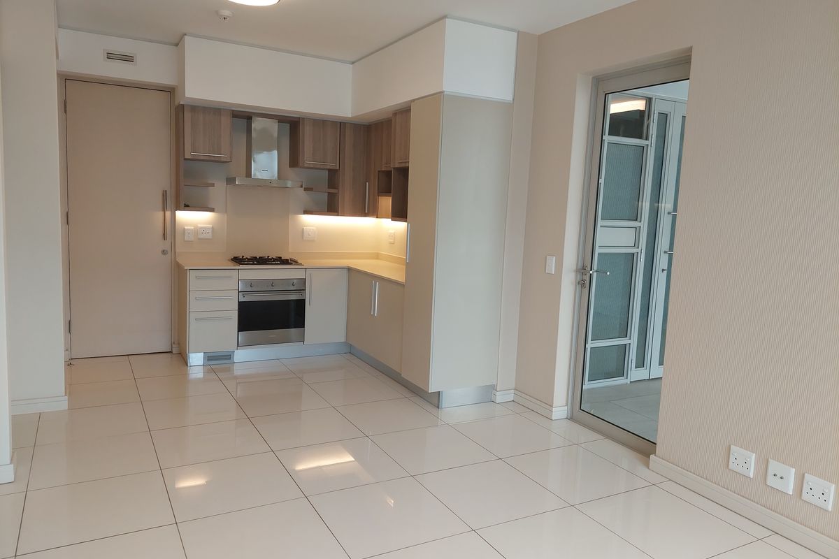 Modern kitchen featuring sleek built-in cabinetry, stone countertops, integrated gas hob, electric oven, and extractor fan, with polished tiled flooring throughout.