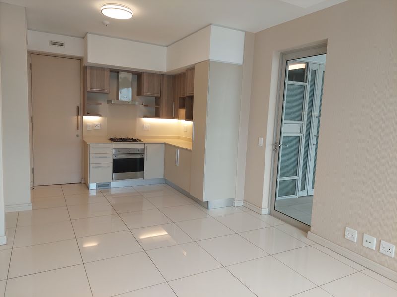 Modern kitchen featuring sleek built-in cabinetry, stone countertops, integrated gas hob, electric oven, and extractor fan, with polished tiled flooring throughout.