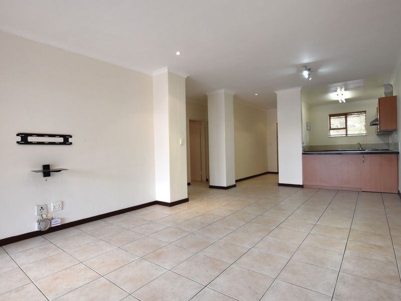 Spacious open-plan living area featuring tiled flooring, recessed lighting, and a functional kitchen with built-in cabinetry and an extractor fan.