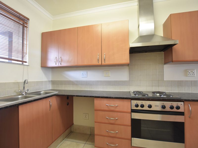 A functional kitchen featuring laminate cabinetry, granite countertops, a built-in oven with electric hob, and a stainless steel extractor fan.