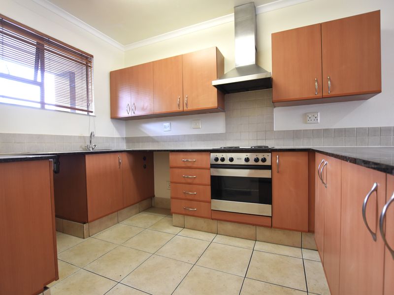 A functional kitchen featuring laminate cabinetry, granite countertops, a built-in oven with extractor fan, and tiled flooring.