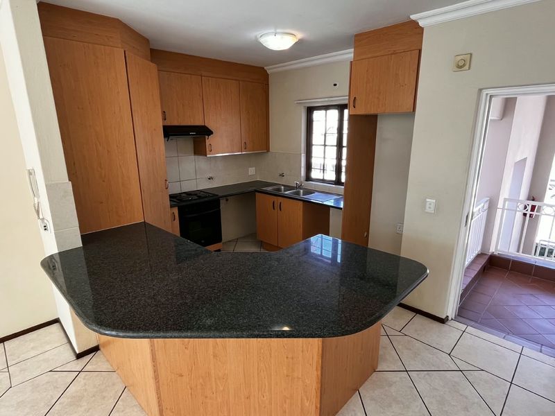 A functional kitchen featuring laminate cabinetry, granite countertops, built-in oven, hob, extractor fan, and tiled flooring, offering a clean and practical workspace.
