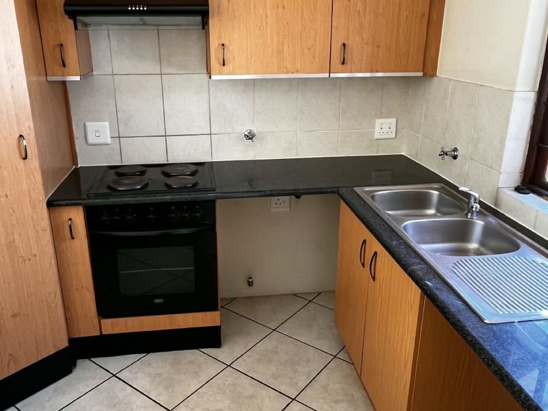 A functional kitchen featuring laminate cabinetry, granite countertops, a double bowl sink, and built-in oven with extractor fan.