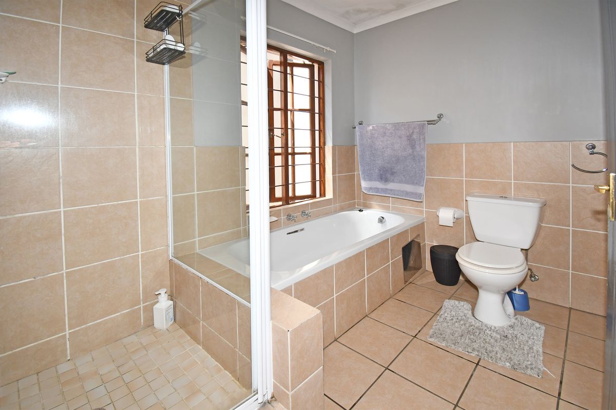 A functional bathroom featuring a tiled shower enclosure with a glass screen, a built-in bathtub, and a standard toilet with ceramic tile finishes.
