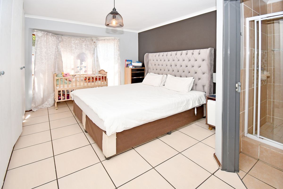 Spacious bedroom featuring tiled flooring, a built-in cupboard, and an attached en-suite shower room.