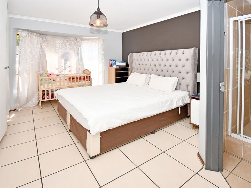 Spacious bedroom featuring tiled flooring, a built-in cupboard, and an attached en-suite shower room.