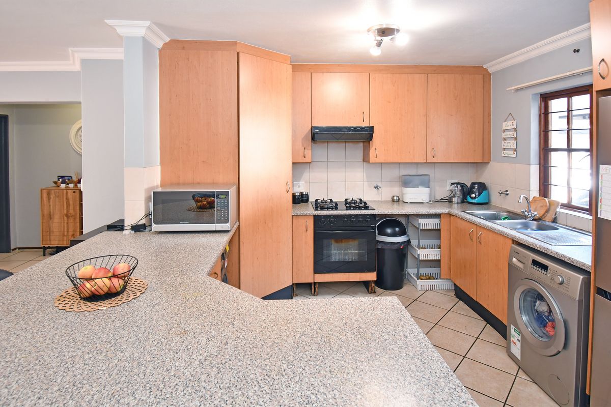 Functional kitchen featuring laminate cabinetry, granite-look countertops, gas hob, built-in oven, and integrated laundry plumbing, offering a practical layout for daily use.