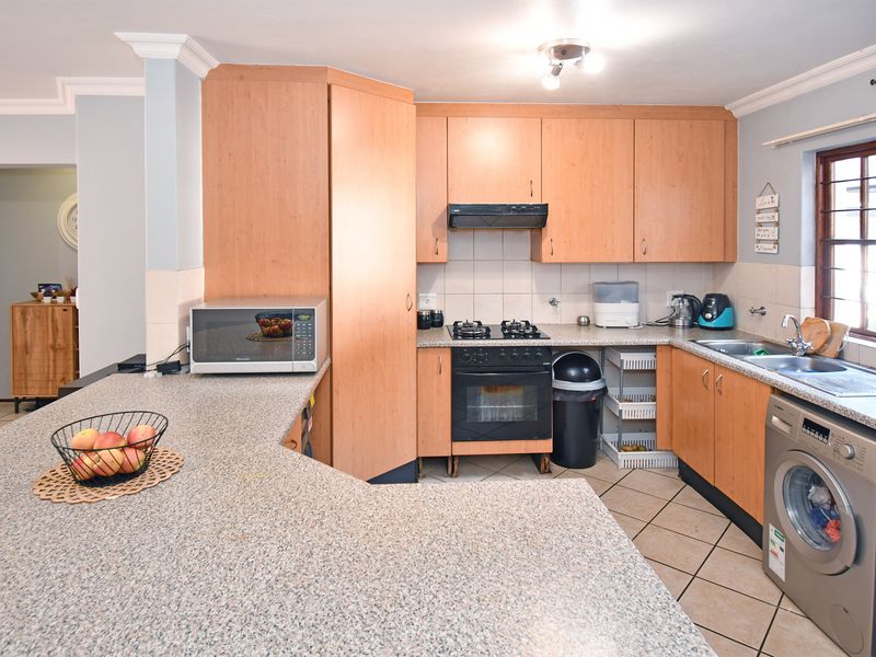 Functional kitchen featuring laminate cabinetry, granite-look countertops, gas hob, built-in oven, and integrated laundry plumbing, offering a practical layout for daily use.