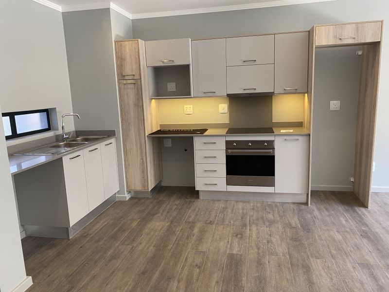 Modern kitchen featuring sleek built-in cabinetry, stone countertops, integrated oven and hob, and high-quality laminate flooring in a clean, contemporary space.