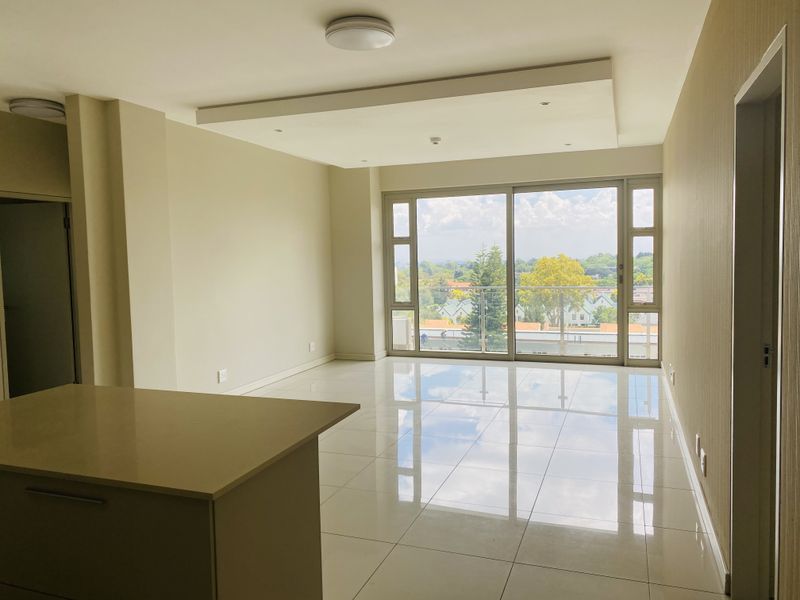 Spacious open-plan living area featuring polished porcelain tiles, a modern recessed ceiling, and large sliding doors opening to a balcony with scenic views.