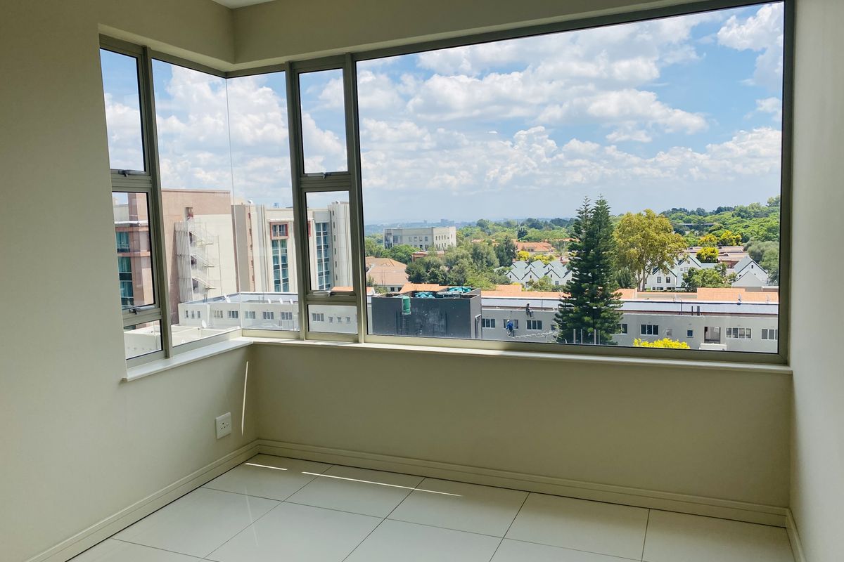 Bright and spacious living area featuring large corner windows that offer expansive neighborhood views and sleek tiled flooring.