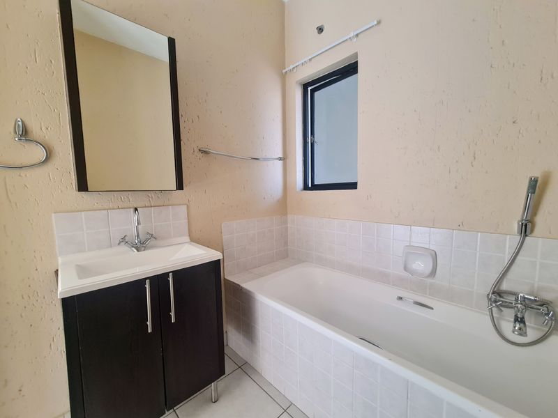 A functional bathroom featuring a vanity with basin, a bathtub with handheld shower attachment, and tiled finishes, ready for a modern update.