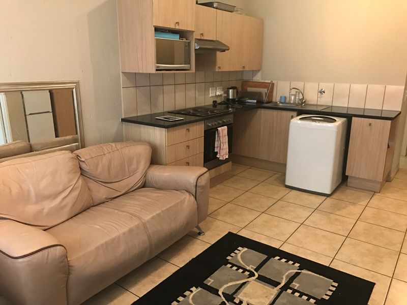 Open plan kitchen and living area featuring laminate cabinetry, black granite countertops, built-in oven, hob, and tiled flooring throughout.