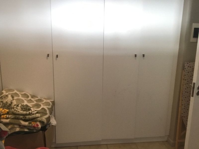 A bedroom featuring white built-in cupboards with simple hardware, providing ample storage space.