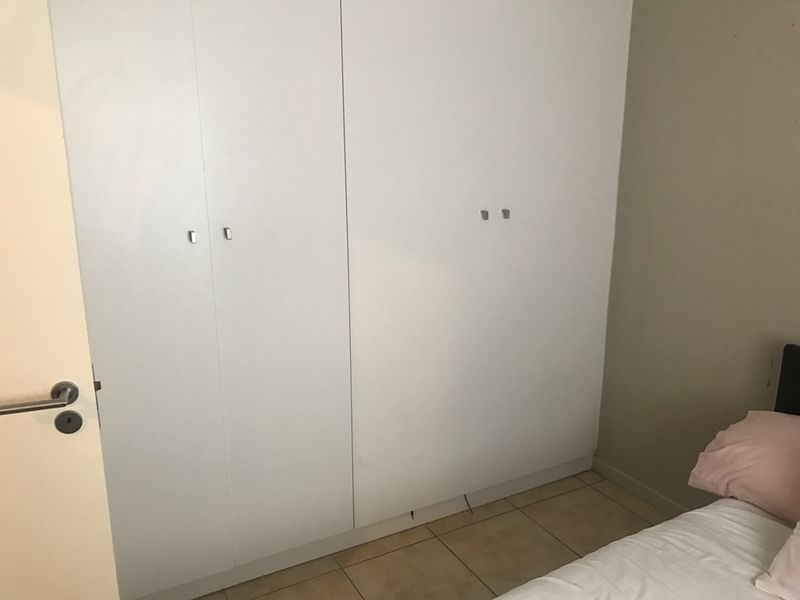 A bedroom featuring built-in cupboards and tiled flooring, offering functional storage space.