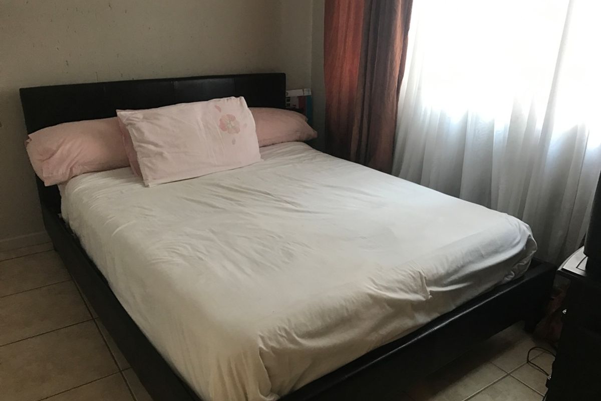 A standard bedroom featuring tiled flooring and a window with curtains.