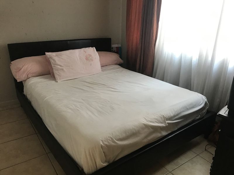 A standard bedroom featuring tiled flooring and a window with curtains.